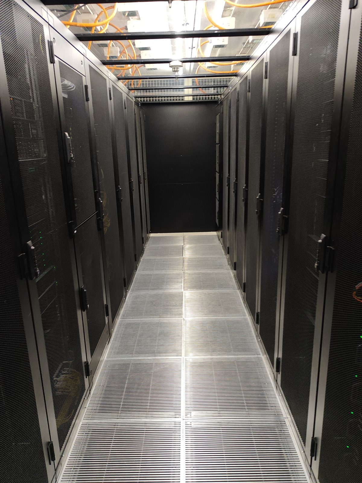 Rangées de baies informatiques dans le cold corridor de la salle colocation standard du datacenter Crissier